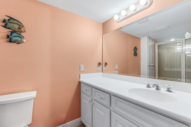 bathroom featuring vanity, a shower with shower door, and toilet