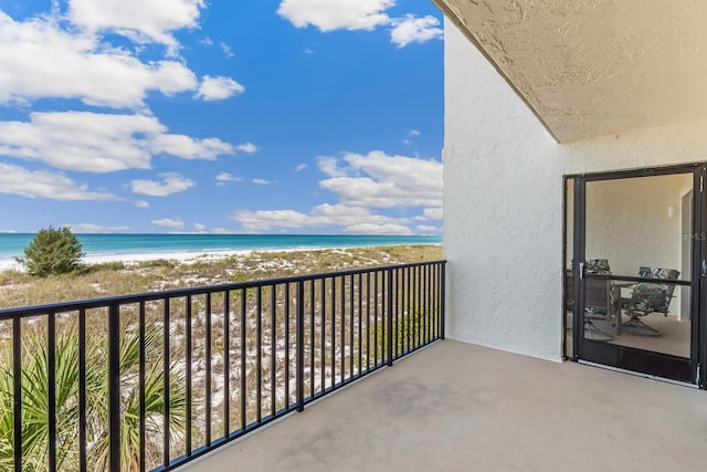 balcony featuring a beach view and a water view