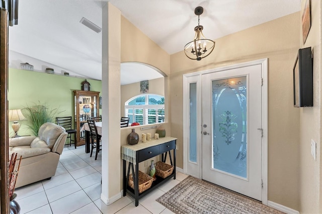 entrance foyer featuring an inviting chandelier, lofted ceiling, and light tile patterned floors