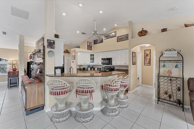 kitchen featuring ceiling fan, kitchen peninsula, black appliances, light tile patterned floors, and white cabinetry