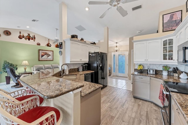 kitchen featuring a kitchen breakfast bar, sink, kitchen peninsula, black appliances, and white cabinetry