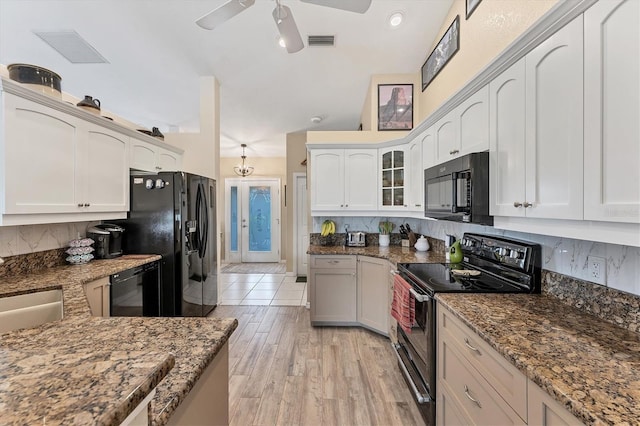 kitchen with white cabinets, light hardwood / wood-style flooring, backsplash, and black appliances