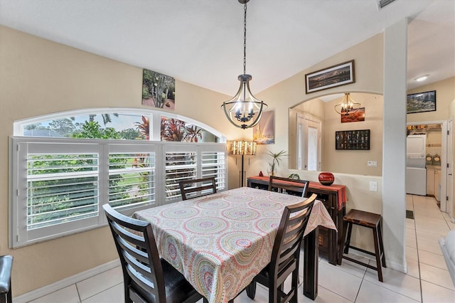 tiled dining space with washer / clothes dryer, vaulted ceiling, and a notable chandelier