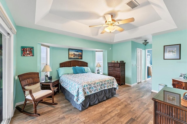 bedroom with a raised ceiling, hardwood / wood-style floors, and ceiling fan