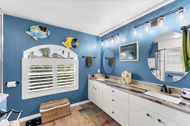 bathroom featuring wood-type flooring, a shower with door, vanity, and a textured ceiling