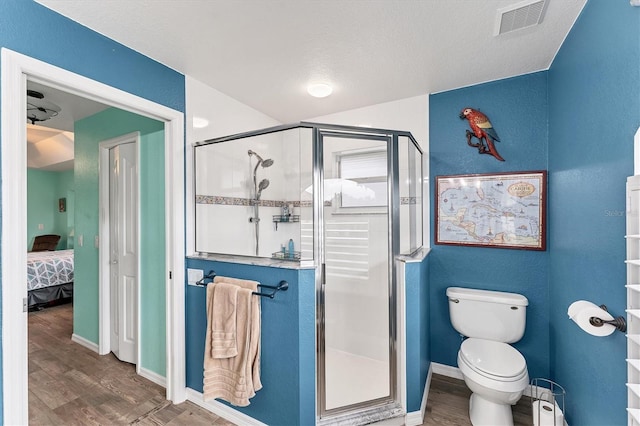 bathroom with an enclosed shower, hardwood / wood-style flooring, a textured ceiling, and toilet