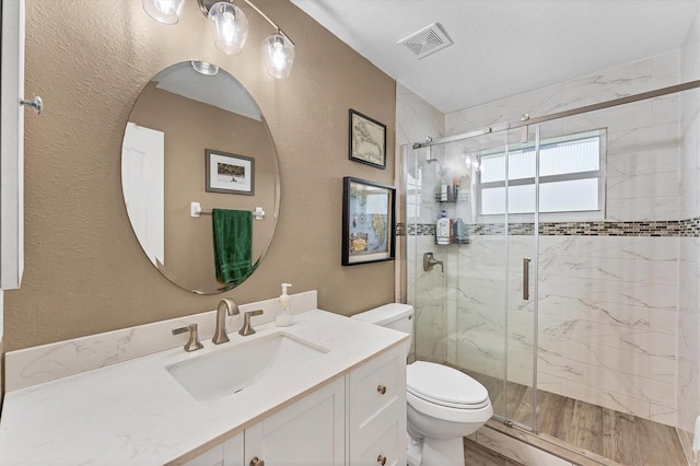 bathroom with a shower with door, hardwood / wood-style floors, vanity, and toilet