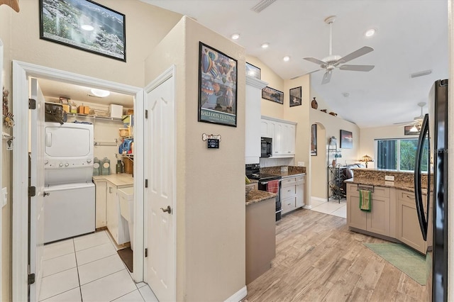 kitchen featuring light wood-type flooring, vaulted ceiling, stacked washer and clothes dryer, white cabinets, and appliances with stainless steel finishes