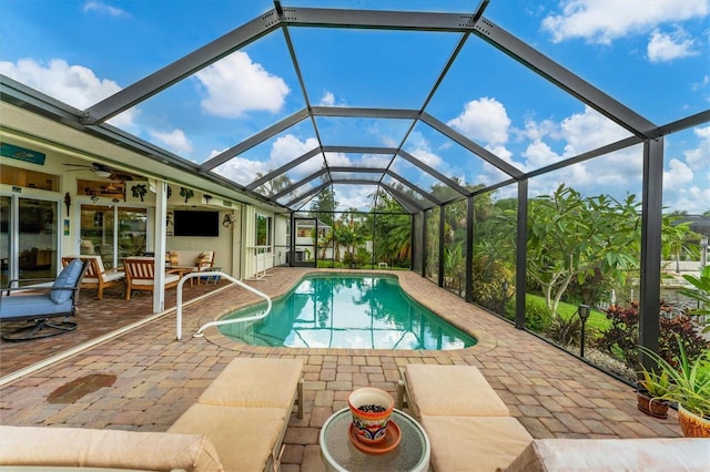 view of swimming pool with ceiling fan, an outdoor living space, glass enclosure, and a patio area