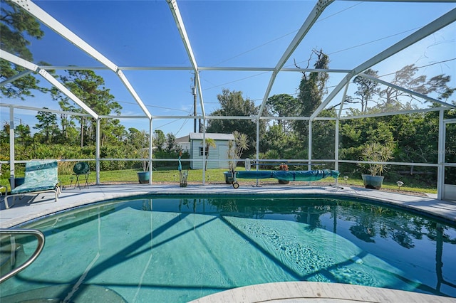 view of pool featuring a storage shed, a patio area, and glass enclosure