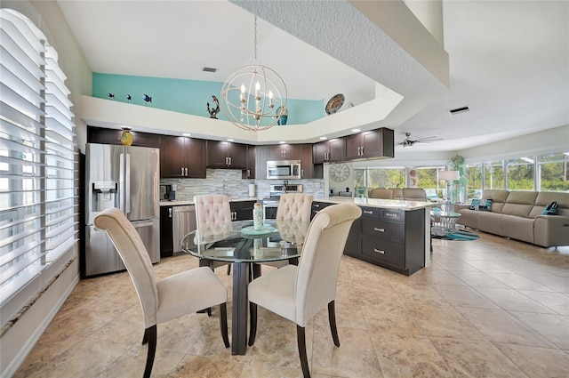 tiled dining room with high vaulted ceiling and ceiling fan with notable chandelier