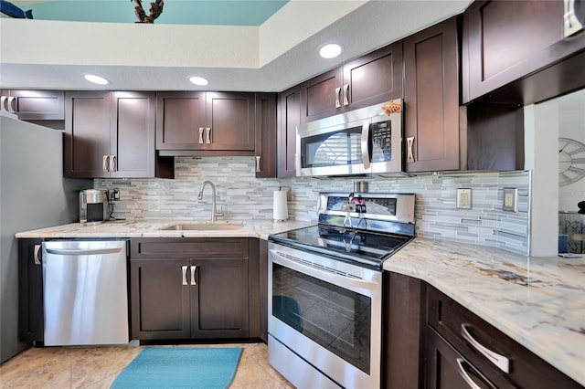 kitchen featuring stainless steel appliances, sink, dark brown cabinetry, light stone counters, and tasteful backsplash