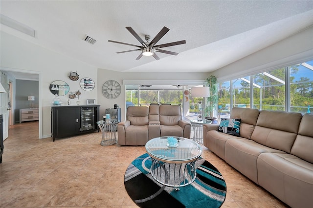 living room with lofted ceiling, a textured ceiling, a healthy amount of sunlight, and ceiling fan