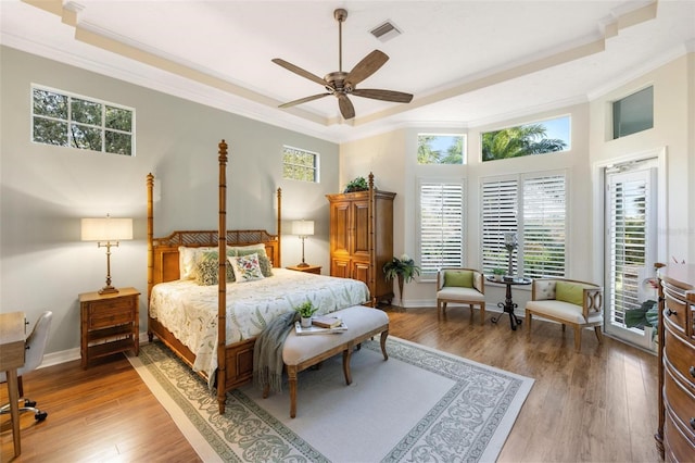 bedroom with a towering ceiling, ceiling fan, wood-type flooring, and ornamental molding