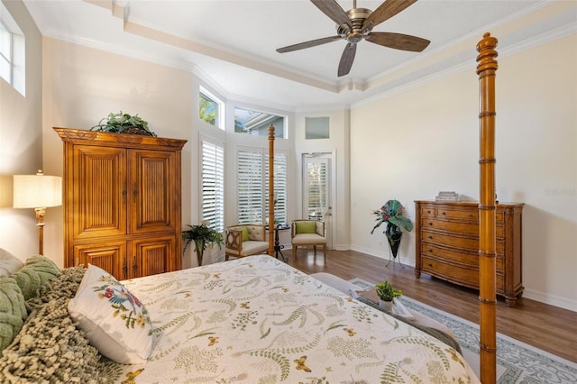 bedroom featuring dark hardwood / wood-style flooring, crown molding, a raised ceiling, and ceiling fan