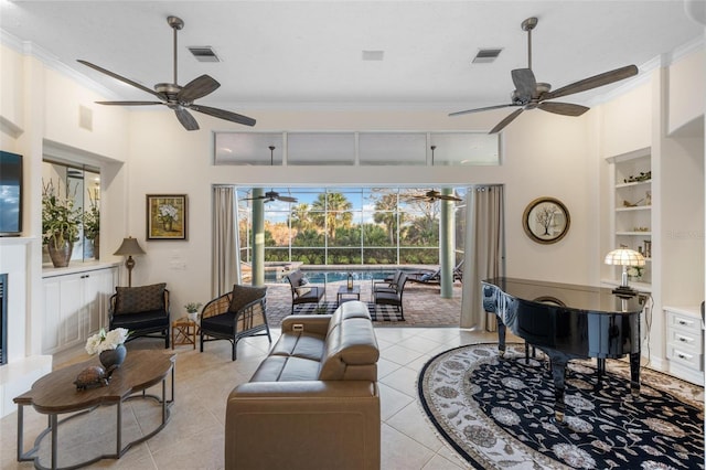 tiled living room featuring a towering ceiling, ceiling fan, crown molding, and built in features