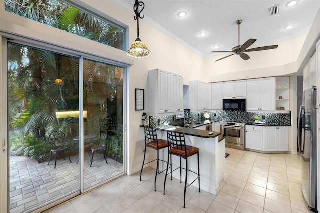 kitchen featuring appliances with stainless steel finishes, kitchen peninsula, white cabinets, and backsplash