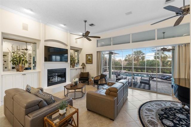 tiled living room featuring ornamental molding, a high ceiling, a textured ceiling, and ceiling fan