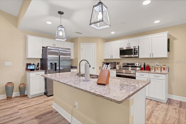 kitchen featuring white cabinets, a center island with sink, appliances with stainless steel finishes, and sink