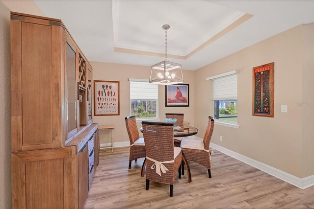 dining space with light hardwood / wood-style floors, a tray ceiling, and an inviting chandelier