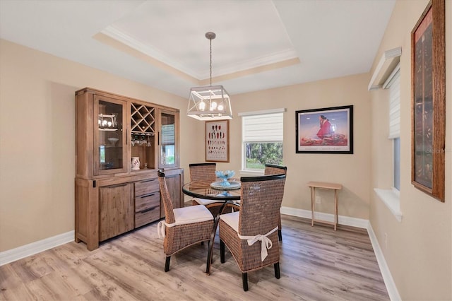 dining space with a raised ceiling, light hardwood / wood-style flooring, and crown molding