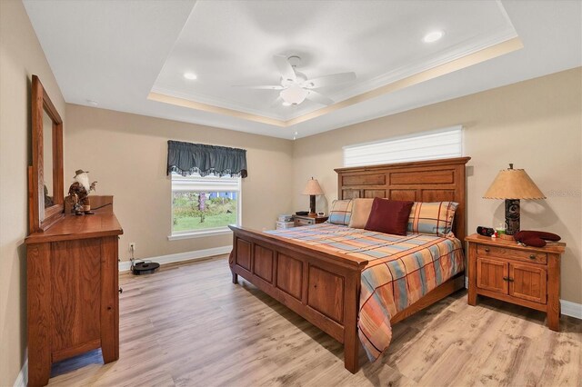 bedroom featuring ceiling fan, light hardwood / wood-style flooring, crown molding, and a tray ceiling