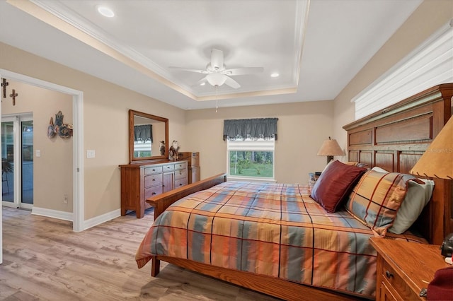 bedroom featuring light wood-type flooring, a tray ceiling, ceiling fan, and crown molding