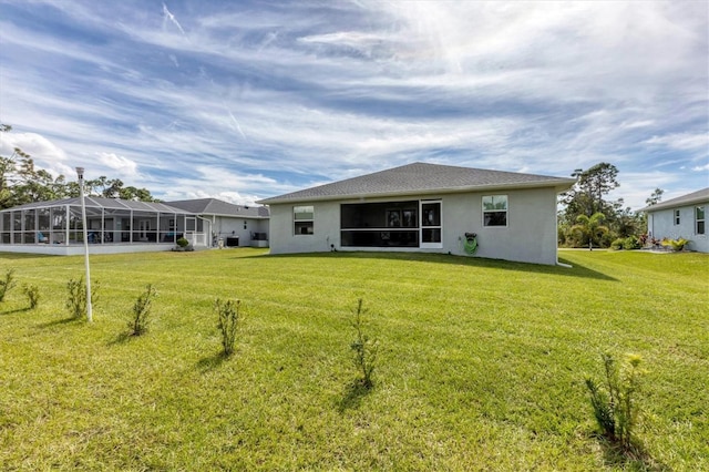 rear view of house with glass enclosure and a lawn