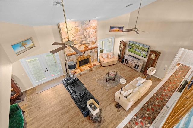 living room featuring a fireplace, hardwood / wood-style flooring, high vaulted ceiling, and ceiling fan