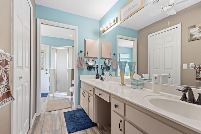 bathroom featuring vanity, toilet, an enclosed shower, and ceiling fan