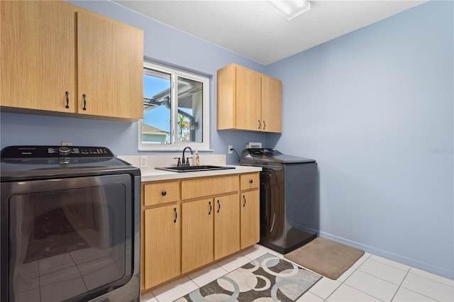 washroom with cabinet space, light tile patterned floors, baseboards, washer and dryer, and a sink