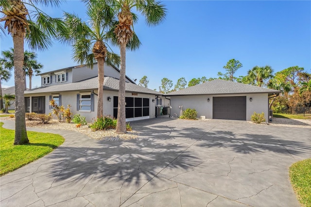 view of front of property featuring a garage, roof with shingles, driveway, and stucco siding