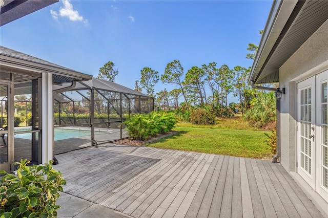 wooden deck featuring a lanai, a yard, an outdoor pool, and french doors