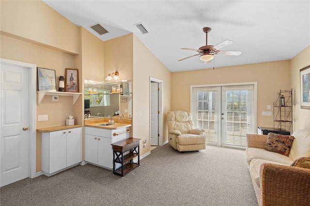 living area with french doors, visible vents, vaulted ceiling, and carpet flooring