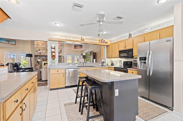 kitchen featuring black appliances, a kitchen bar, a kitchen island, and visible vents