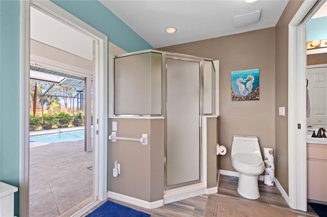 bathroom featuring baseboards, toilet, wood finished floors, vanity, and a shower stall