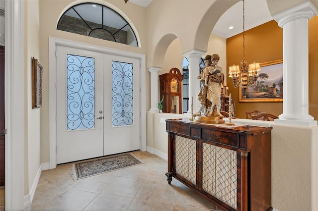 tiled entryway with french doors, a notable chandelier, and a towering ceiling