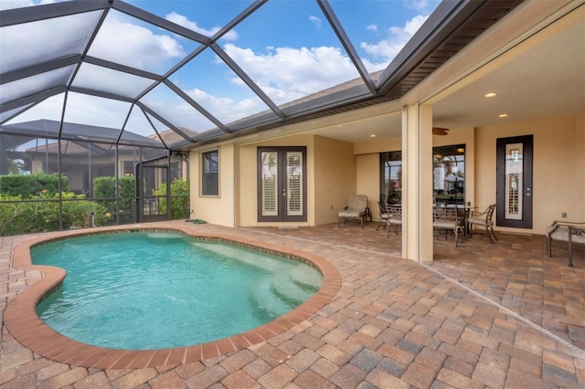 view of pool featuring glass enclosure, a patio area, and ceiling fan