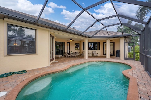 view of swimming pool featuring ceiling fan, glass enclosure, and a patio area