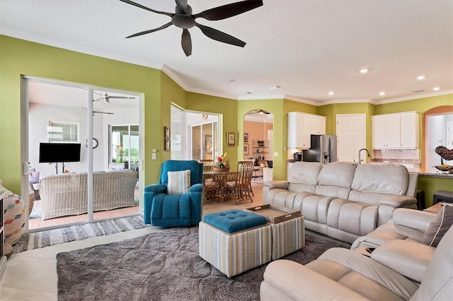 living room featuring ceiling fan, sink, tile patterned flooring, and ornamental molding