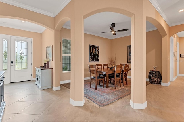 tiled dining area with ceiling fan and crown molding