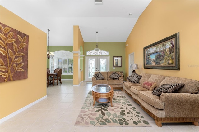 tiled living room with french doors, ornate columns, high vaulted ceiling, and a chandelier