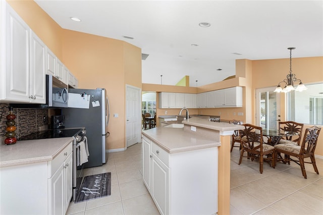 kitchen with stainless steel appliances, a kitchen island with sink, sink, and white cabinets