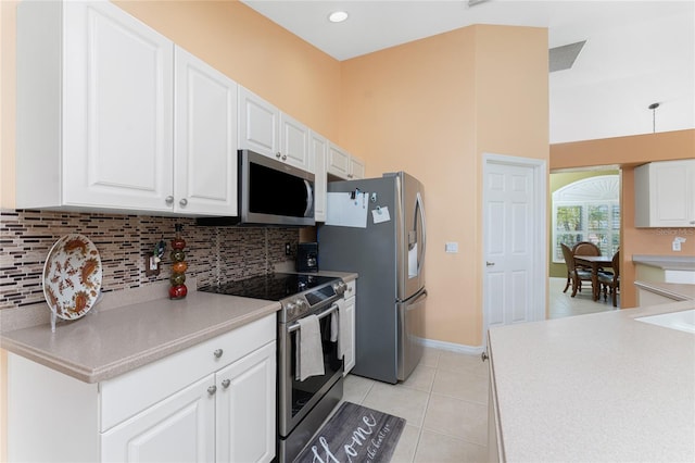 kitchen featuring white cabinets, stainless steel appliances, tasteful backsplash, and light tile patterned floors