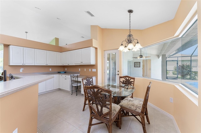 tiled dining area with high vaulted ceiling and ceiling fan with notable chandelier