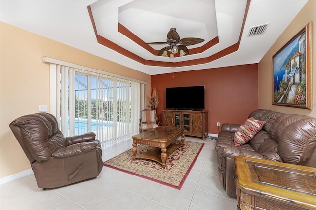 tiled living room featuring a raised ceiling and ceiling fan