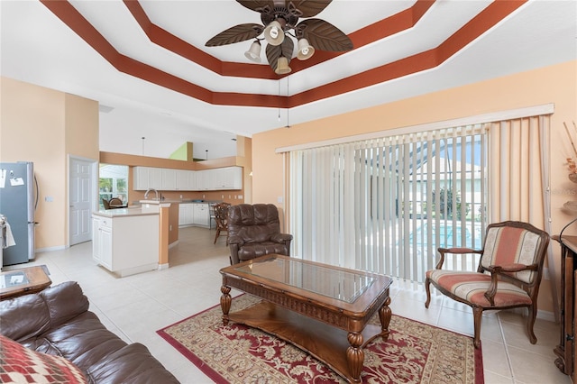 living room featuring light tile patterned flooring, sink, a raised ceiling, and ceiling fan