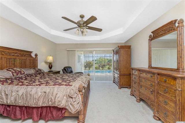 bedroom with light colored carpet, a tray ceiling, access to outside, and ceiling fan