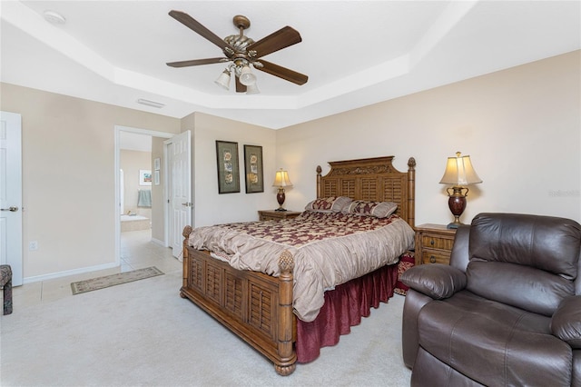 carpeted bedroom with connected bathroom, a tray ceiling, and ceiling fan