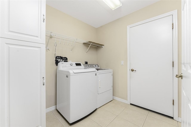 laundry area with washing machine and dryer and light tile patterned floors